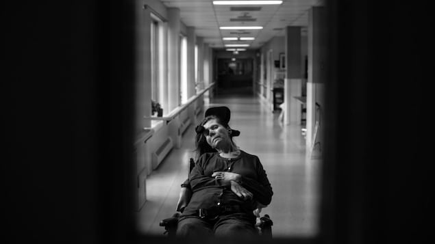 Jamie Woytiuk a photographié sa mère dans son fauteuil roulant, la tête tombant du côté gauche. Derrière elle, il y a un long corridor. Jamie Woytiuk a photographié sa mère dans son fauteuil roulant, la tête tombant du côté gauche. Derrière elle, il y a un long corridor.