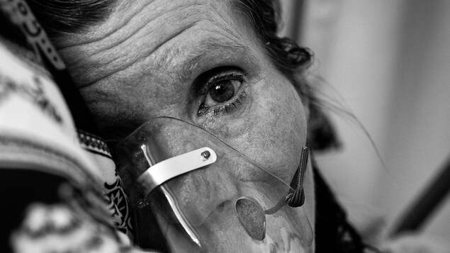 La mère de Jamie Woytiuk, Joanne, est couchée sur le côté. Elle a un masque à oxygène sur le nez et la bouche. On ne voit que sa tête. Elle regarde fixement l'objectif de l'appareil photo. La mère de Jamie Woytiuk, Joanne, est couchée sur le côté. Elle a un masque à oxygène sur le nez et la bouche. On ne voit que sa tête. Elle regarde fixement l'objectif de l'appareil photo.