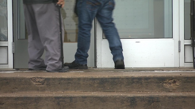 Les jambes de deux hommes devant une porte.