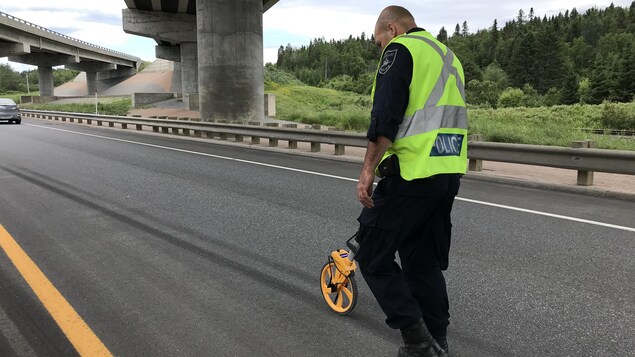 Pierre Girard utilisant un appareil pour mesurer la longueur d'une trace de freinage. Pierre Girard utilisant un appareil pour mesurer la longueur d'une trace de freinage.