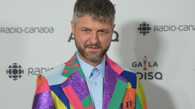 Le chanteur est vêtu d'un veston de couleurs différentes.