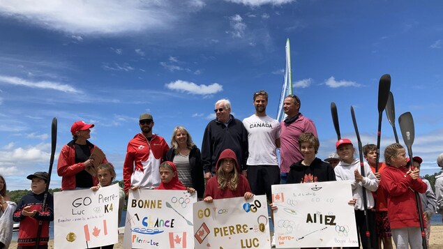 Des gens se tiennent sur et devant un podium avec des pancartes.