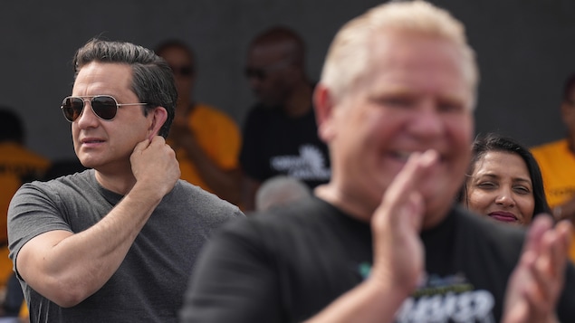 Doug Ford, flou au premier plan, et Pierre Poilievre derrière lui dans une foule lors d'un rassemblement culturel.