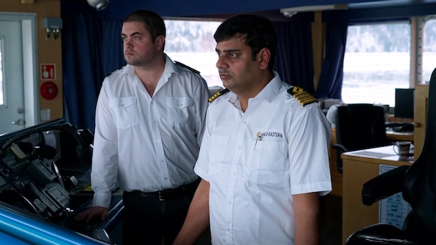 Deux hommes habillés en blanc, dont un capitaine, dans un bateau.