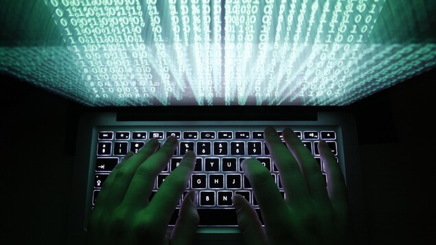 Un homme tape sur un clavier d'ordinateur. 