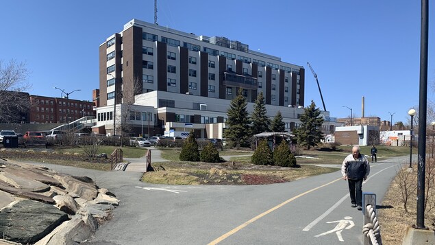 Un homme marche sur un trottoir longeant le lac Osisko, derrière l'hôpital de Rouyn-Noranda.