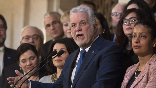 Le premier ministre Philippe Couillard fait le bilan de sa session parlementaire, accompagné de ses ministres. Le premier ministre Philippe Couillard fait le bilan de sa session parlementaire, accompagné de ses ministres.