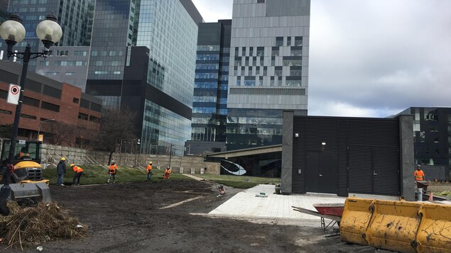 Des ouvriers s'affairent sur la nouvelle place publique au cœur de Montréal. Des ouvriers s'affairent sur la nouvelle place publique au cœur de Montréal.