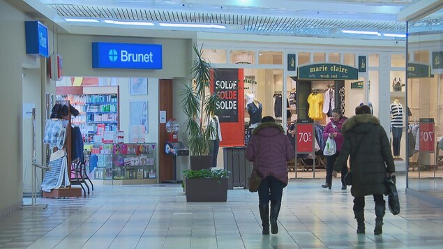 Des clients avec leur manteau marchent dans le corridor de Place du Saguenay.