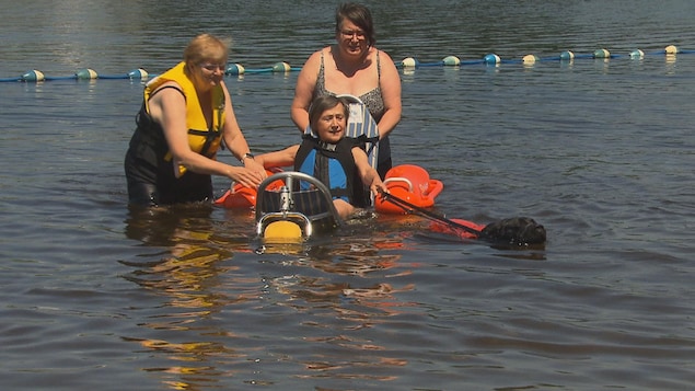 Une dame dans un fauteuil adapté dans l'eau.