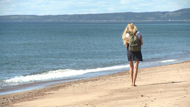 Une jeune femme marche sur la plage de Val-Marguerite, à Sept-Îles.