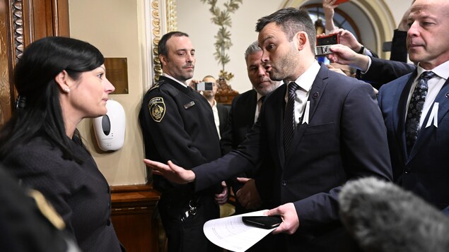 Le chef du Parti québécois Paul St-Pierre Plamondon, au centre, s'adresse au sergent d'armes de l'Assemblée nationale Véronique Michel.