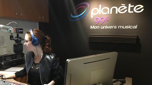 Une femme avec des écouteurs regarde son écran d'ordinateur. Elle est entourée de sa console de radio. Une femme avec des écouteurs regarde son écran d'ordinateur. Elle est entourée de sa console de radio.