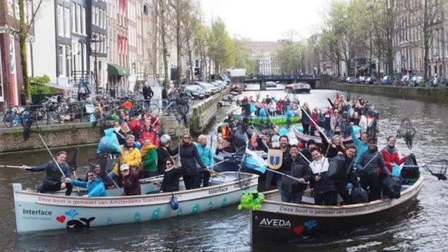 Des touristes sont dans des embarcations pour repêcher les déchets en plastique qui flottent sur les canaux d'Amsterdam. Des touristes sont dans des embarcations pour repêcher les déchets en plastique qui flottent sur les canaux d'Amsterdam.