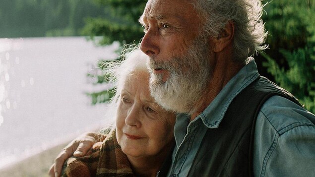 Un couple âgé se serre près d'un lac.