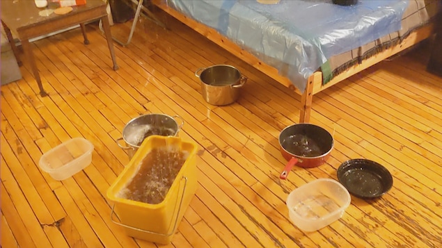 Des plats de plastique, des chaudrons et des poêles recueillent l'eau qui tombe du plafond.