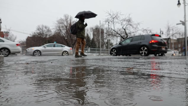 Un homme traverse la rue, inondée d'eau de pluie Un homme traverse la rue, inondée d'eau de pluie