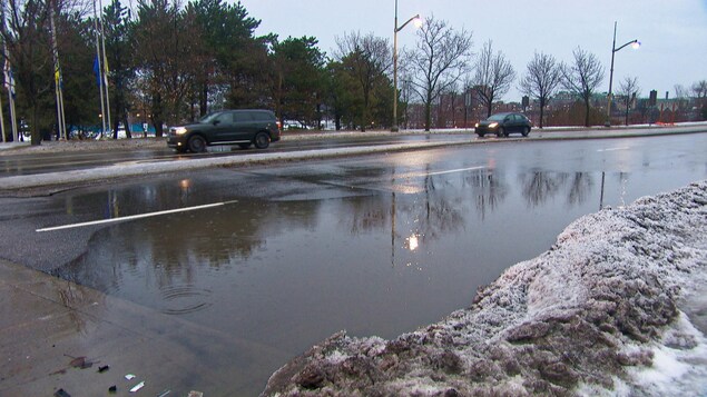 Une flaque d'eau occupe toute une voie d'une rue de Gatineau. Des voitures circulent dans l'autres voies.