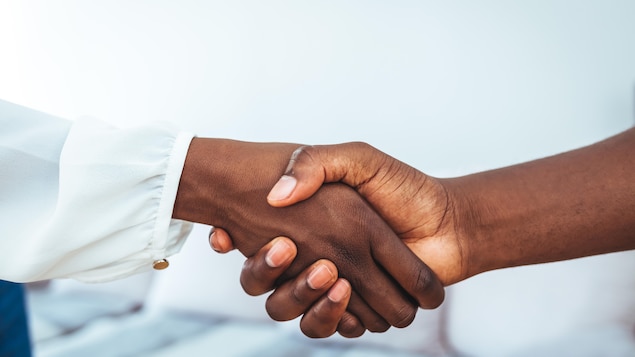 Une femme et un homme noirs échangent une poignée de main.