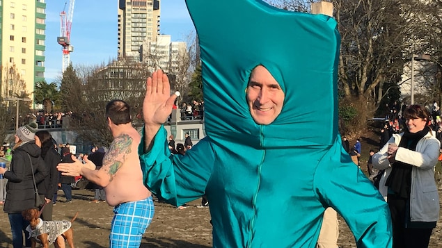Un homme portant un déguisement vert salue de la main. Un homme portant un déguisement vert salue de la main.