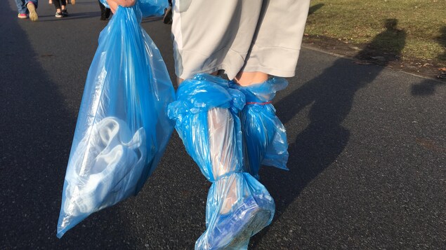 Un homme qui se promène avec les pieds emballés dans un sac de recyclage bleu. Un homme qui se promène avec les pieds emballés dans un sac de recyclage bleu.