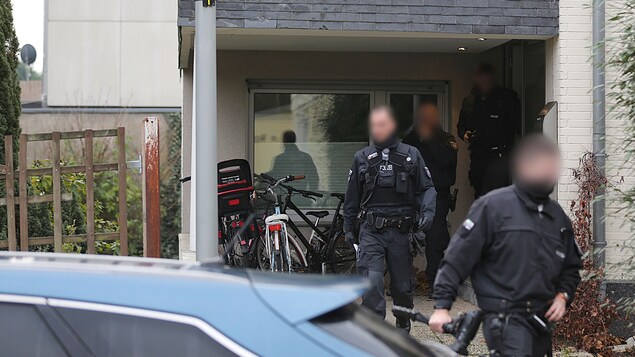 Des agents de police sortent d'une maison.