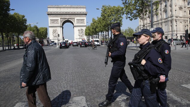 Trois policiers français armés traversent les Champs-Élysées. Trois policiers français armés traversent les Champs-Élysées.