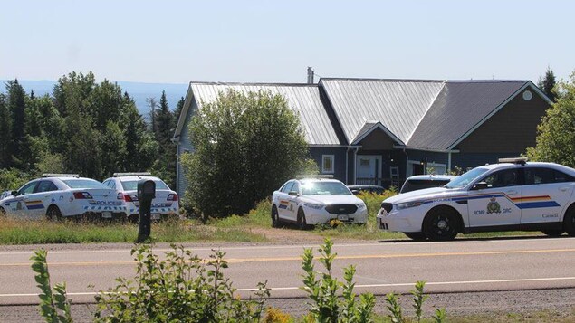 Quatre voitures de la GRC stationnées tout autour d'une grande maison.