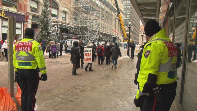 Des policiers d'Ottawa avec des vestes jaunes surveillent des manifestants pro-vie sur la rue Sparks, à Ottawa. Des policiers d'Ottawa avec des vestes jaunes surveillent des manifestants pro-vie sur la rue Sparks, à Ottawa.