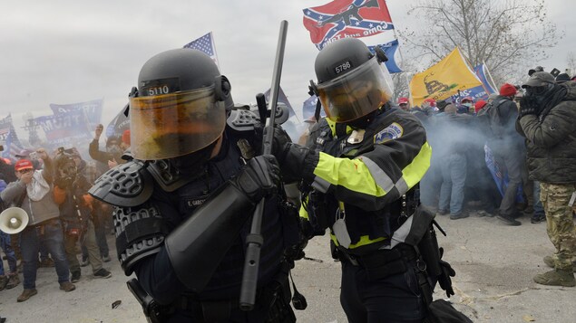 Deux policiers tournant le dos à des centaines de manifestants.