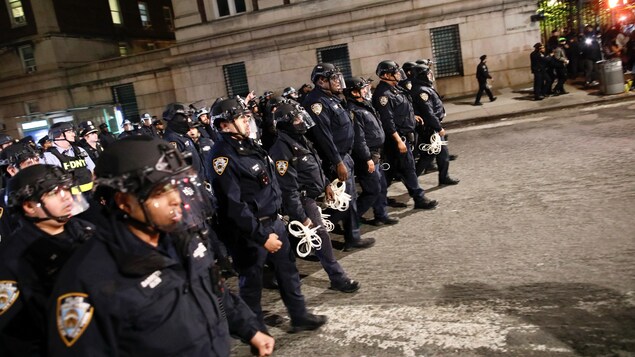 Des agents de la police de New York en tenue anti-émeute entrent dans le campus de l'université de Columbia.