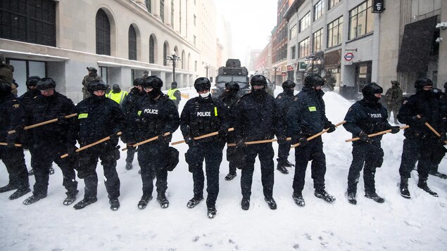 Des policiers en rangée armés de bâtons.