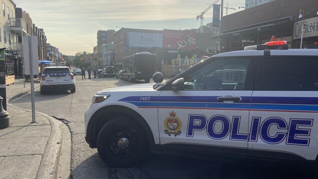 Une voiture de police d'Ottawa, stationnée perpendiculairement à la rue Clarence. Trois policiers sont au centre de la rue, parlant à une personne. 