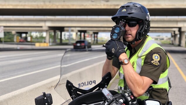 Un policier tient un radar dans ses mains.