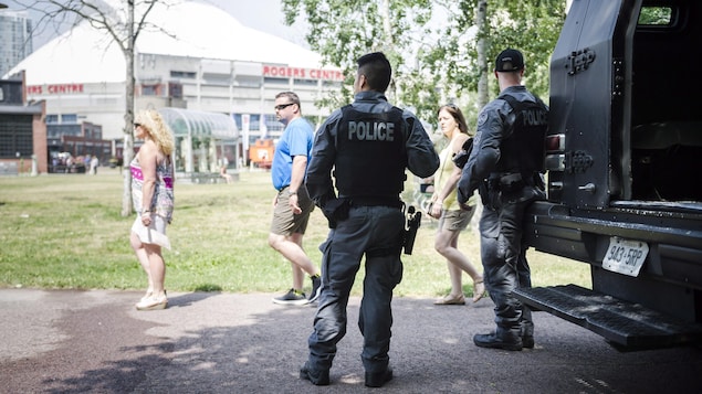 Des policiers et des passants devant le Centre Rogers au centre-ville de Toronto. Des policiers et des passants devant le Centre Rogers au centre-ville de Toronto.