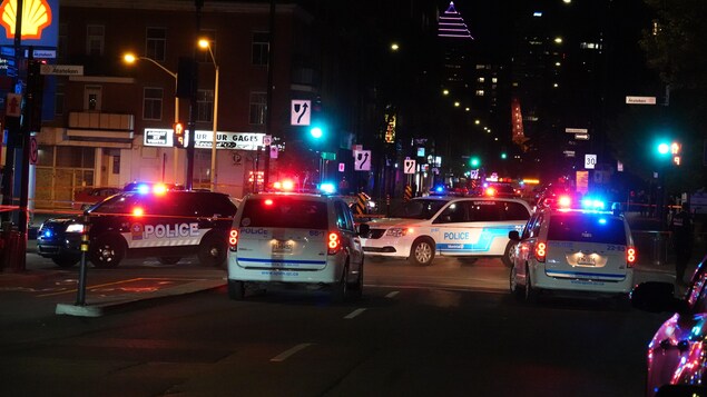 Des voitures de polices stationnées autour d'un périmètre de sécurité. 