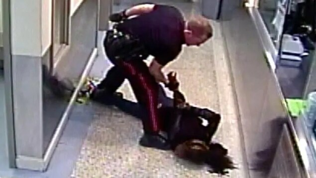 Un policier plaque au sol une femme menottée.