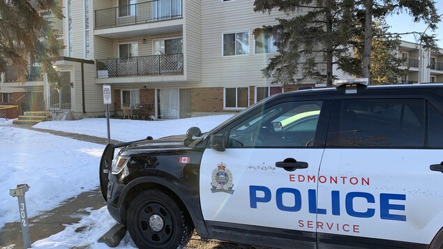 Une voiture de police stationnée à l'arrière d'un immeuble à appartement. 