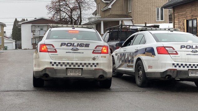 Deux voitures de police dans une rue.