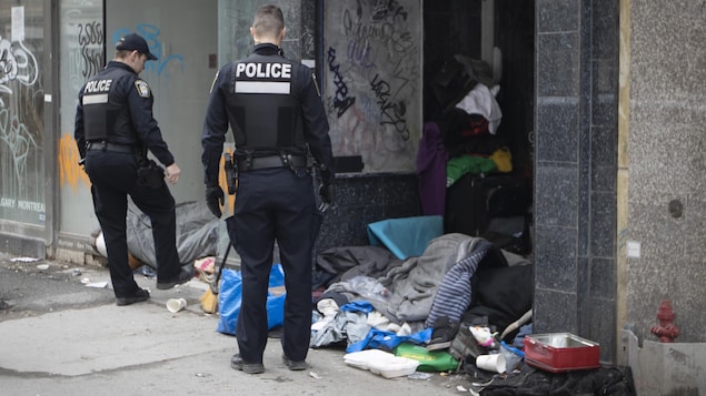 Deux policiers près d'un espace occupé par des sans-abri à Montréal.