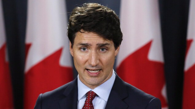 Le premier ministre Justin Trudeau devant des drapeaux canadiens.