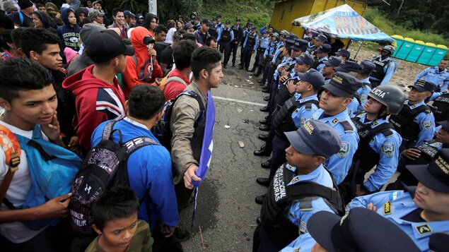 Des migrants se tenant devant des policiers. Des migrants se tenant devant des policiers.