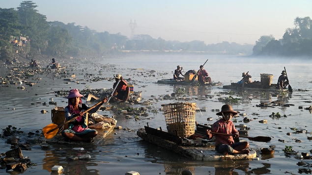 Une dizaine de personnes flottent sur des embarcations de polystyrène à la recherche de plastique et de verre à recycler parmi les déchets qui flottent dans la crique de Pazundaung, à Rangoon, au Myanmar.