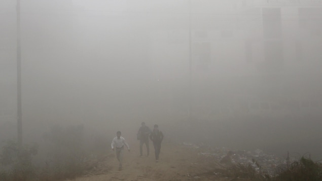 Des habitants de New Delhi émergent du nuage de pollution qui enveloppe la ville. La photo a été prise en plein jour.
