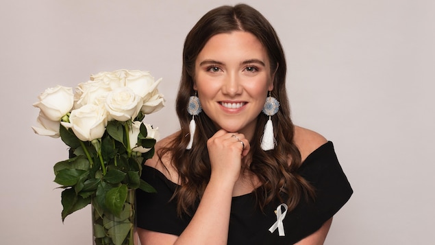 Brielle Thorsen, lauréate de l’Ordre de la rose blanche remis par Polytechnique Montréal pose à côté d'un bouquet de roses blanches