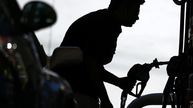 Silhouette d'un homme observant le prix de l'essence à la pompe.