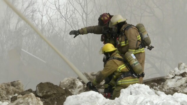 Des pompiers arrosent un incendie.