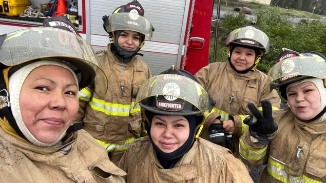 Des femmes en habit de pompier posent pour la photo.