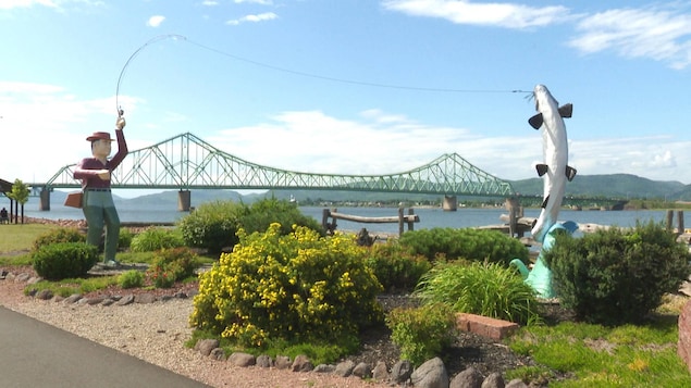 Des monuments qui représentent un pêcheur et un poisson, avec le pont en arrière.