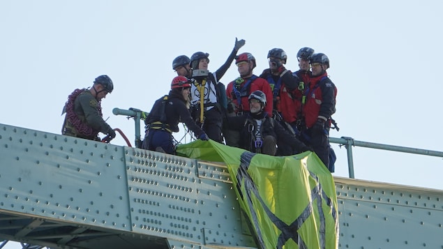 Une femme tient le bras en l'air en signe de victoire sur la structure du pont Jacques-Cartier.